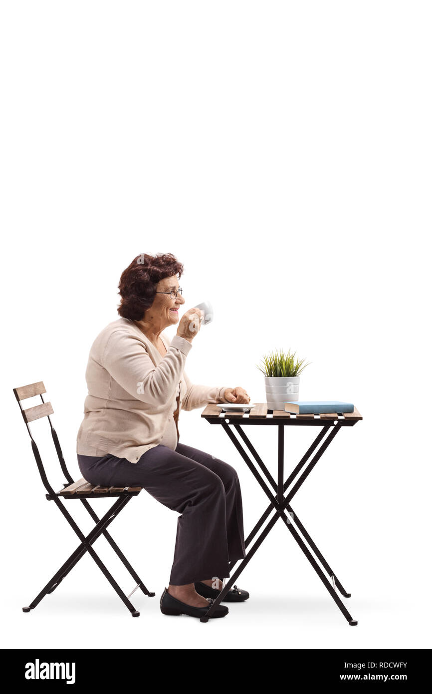 Volle Länge Profil geschossen von einer älteren Frau trinkt Kaffee an einem Tisch auf weißem Hintergrund Stockfoto