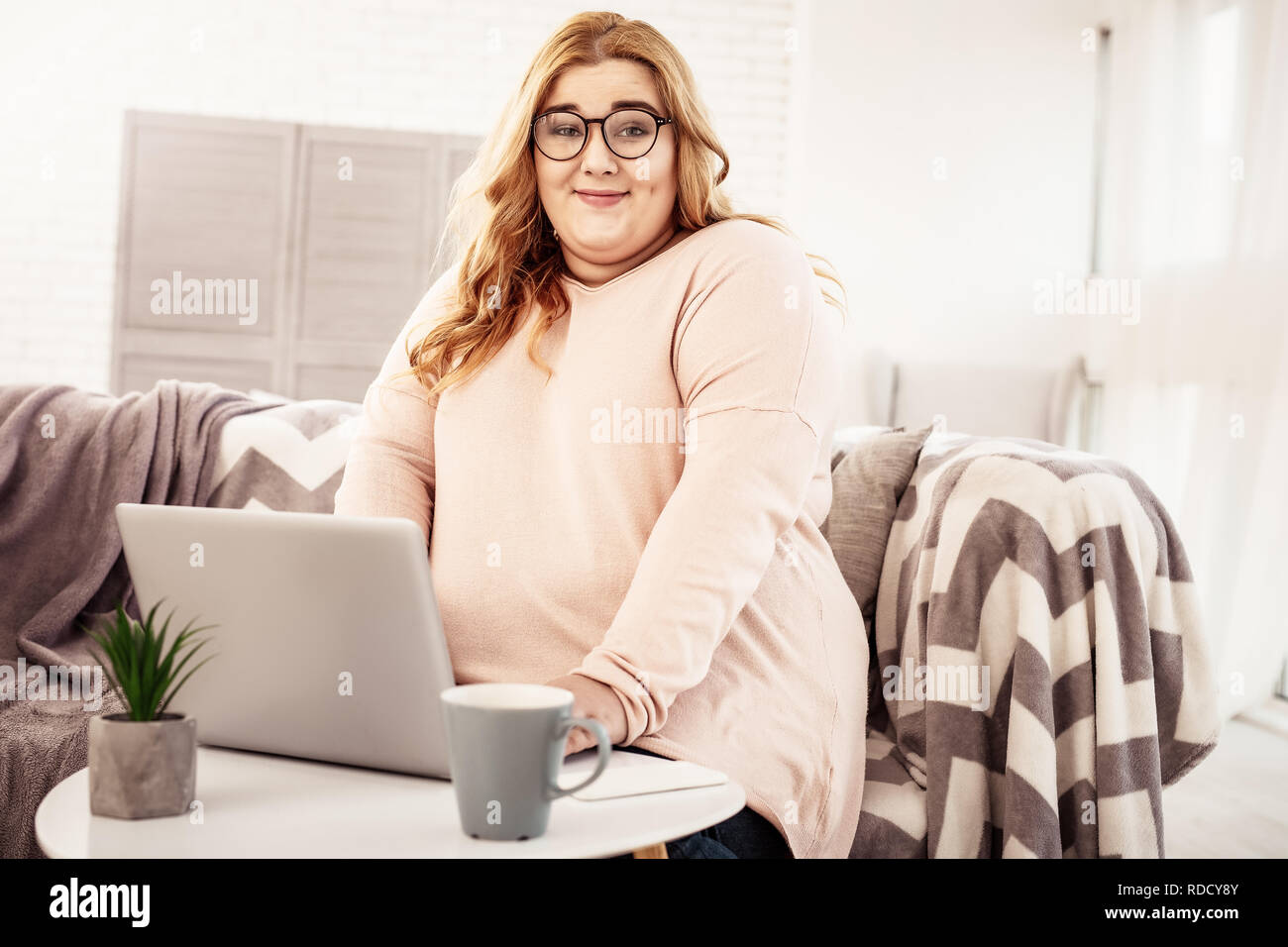 Unbeholfen übergewichtige Frau sitzt mit ihrem Laptop Stockfoto