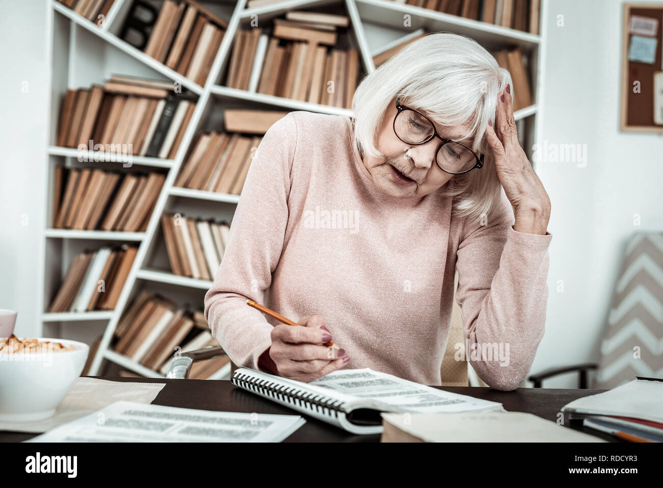 Aufmerksame ältere weibliche Person Aufgabe Lesen bewusst Stockfoto