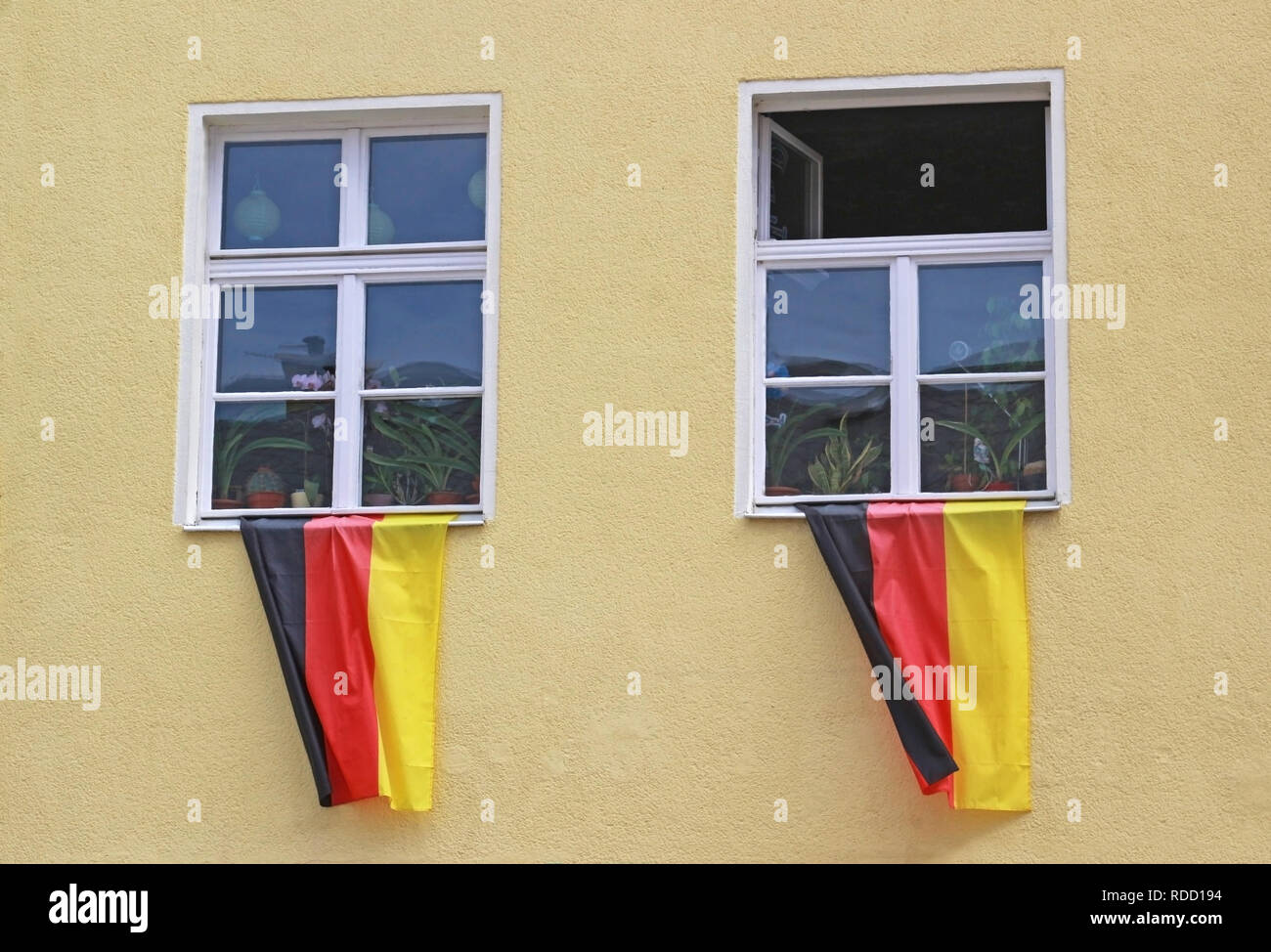 Der deutsche Nationalismus: Deutsche Fahnen winken von zwei fensterbänke eines alten gelben Haus Stockfoto