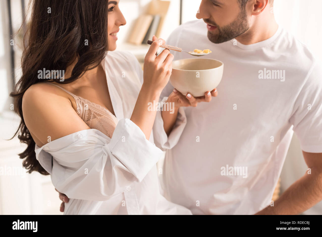 Frau füttern Mann mit Müsli beim Frühstück am Morgen Stockfoto