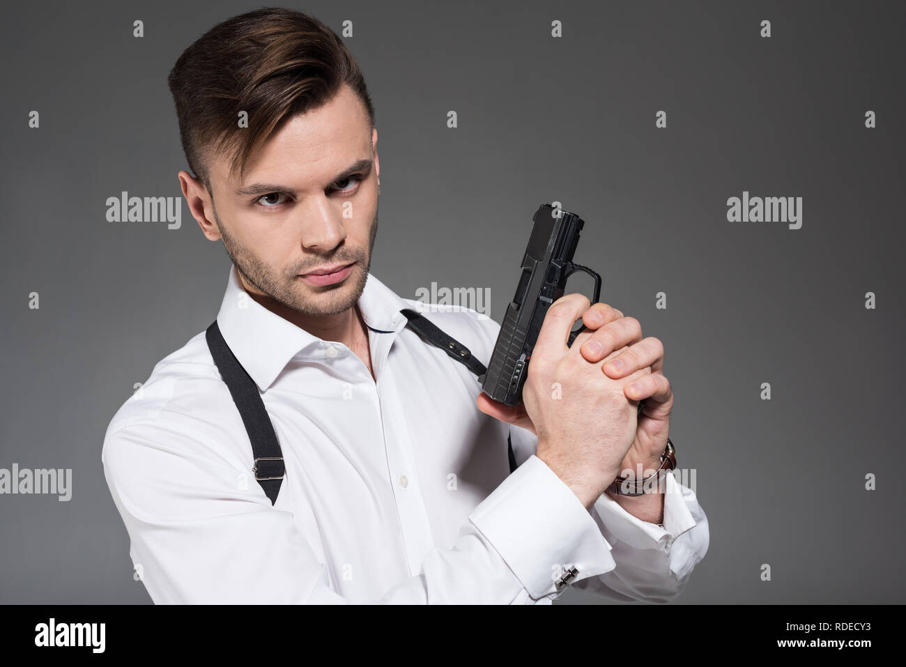 Stattliche Secret Agent mit Holster holding Pistole, isoliert auf Grau Stockfoto