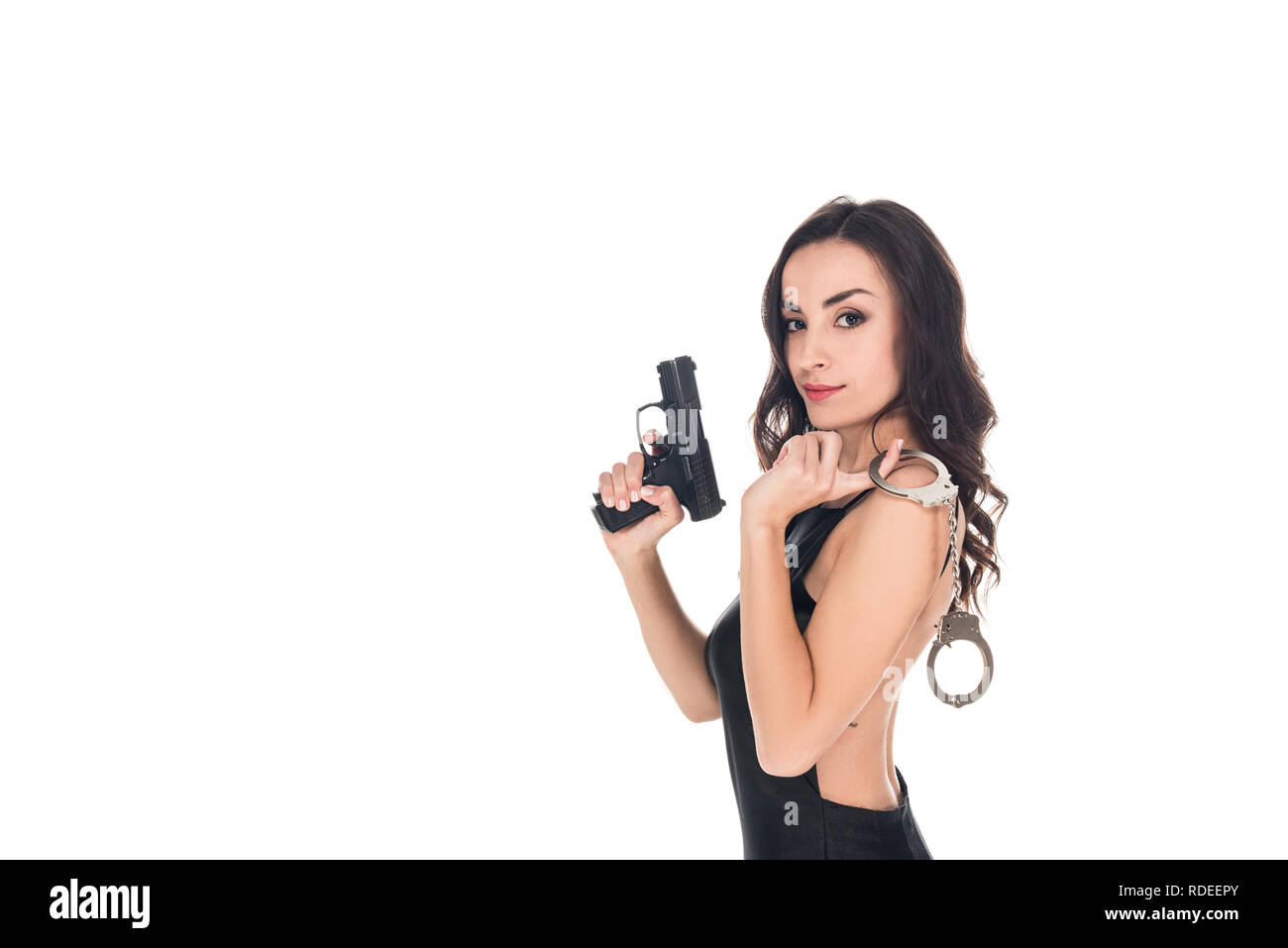 Schöne Security Agent in schwarzem Kleid holding Gun und Handschellen, isoliert auf weißem Stockfoto