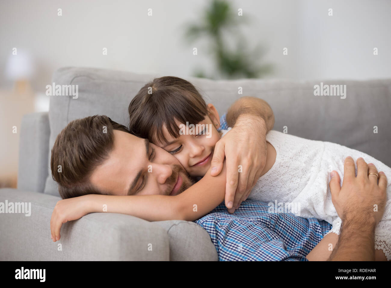 Gerne Vater umarmt niedliche Kind zusammen ruhen auf komfortable Stockfoto