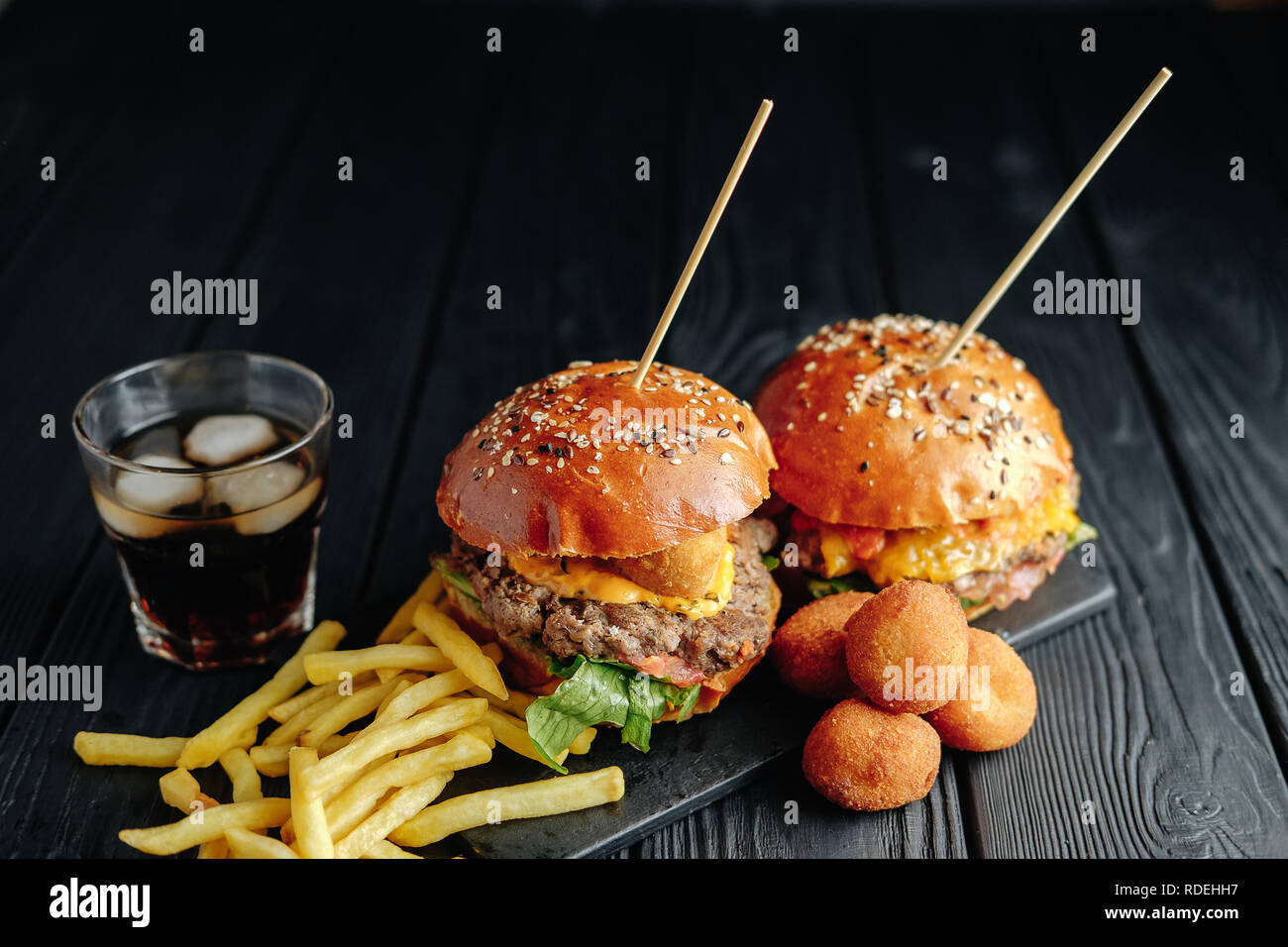 Zwei selbstgemachte Burger mit Speck Käse Kugeln Pommes und ein Glas ...