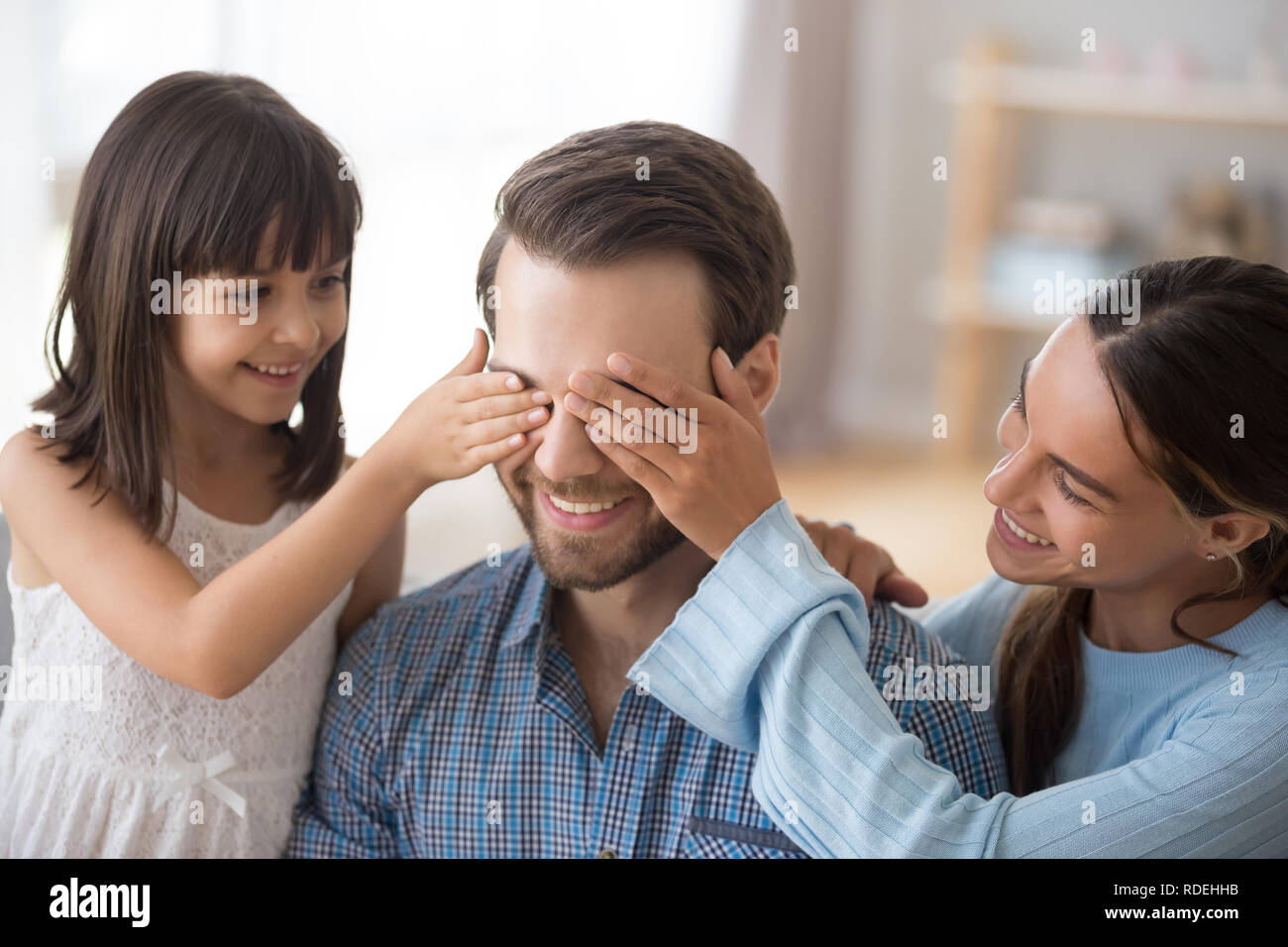 Frau mit Kind schließen Augen von lächelnden Papa Überraschung machen Stockfoto