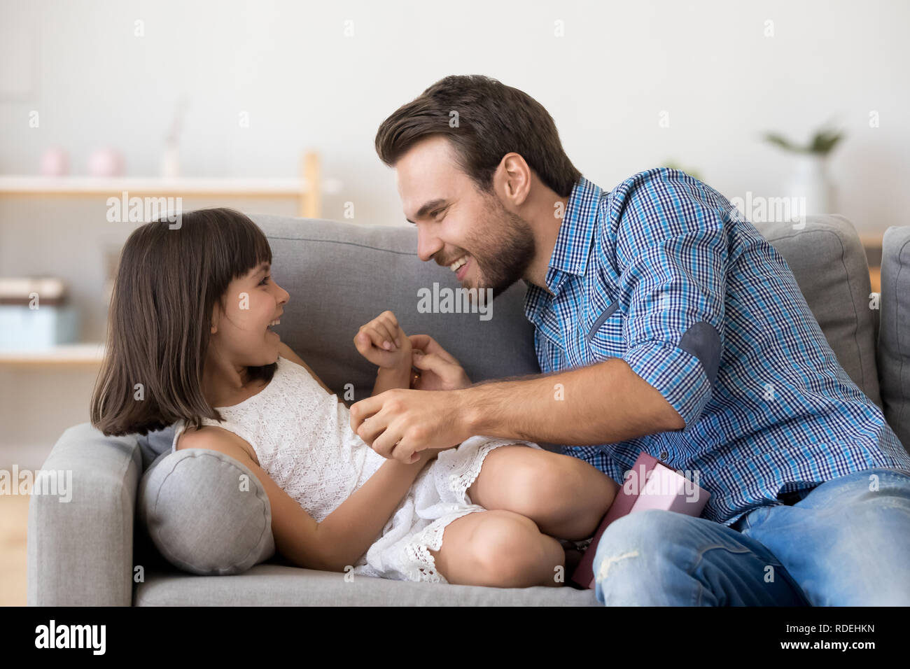 Happy Daddy und niedlichen Tochter spielen gemeinsam Kitzeln auf dem Sofa Stockfoto