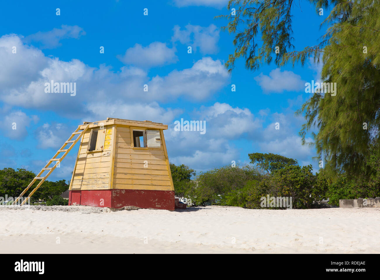 Die ursprüngliche gelb Holz- lifeguard Station auf Enterprise Beach, Barbados, gebadet in strahlend blauem Himmel mit puffy Clouds. Stockfoto