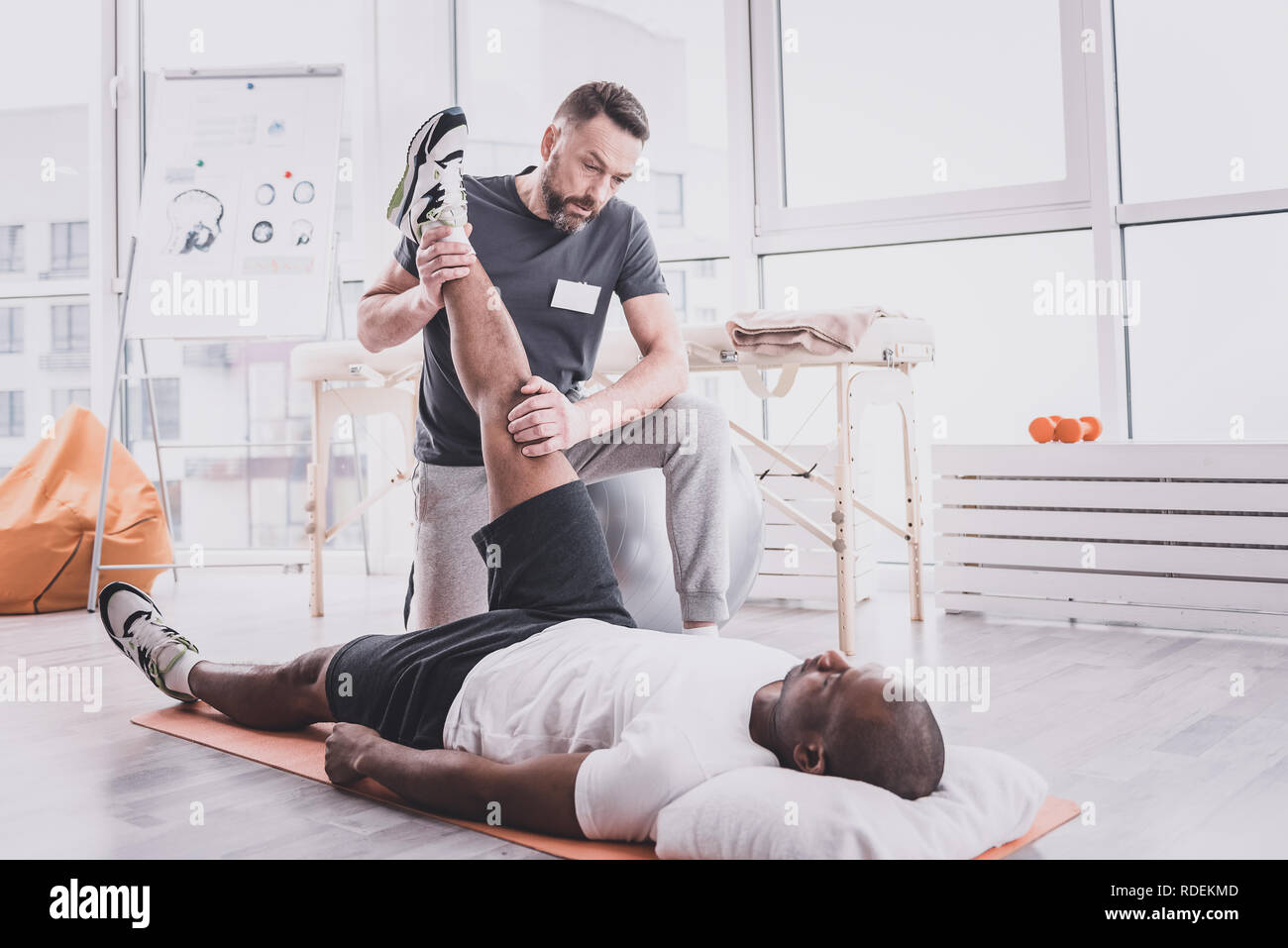 Schwere Arzt stretching Bein des Patienten Stockfoto