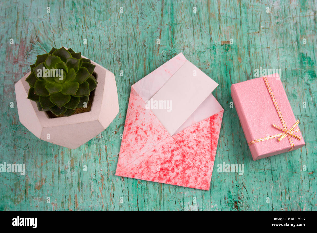 Ansicht von oben rosa Geschenk, saftigen potbox und Umschlag mit weißem Papier mock up schäbig Holz- Hintergrund Stockfoto