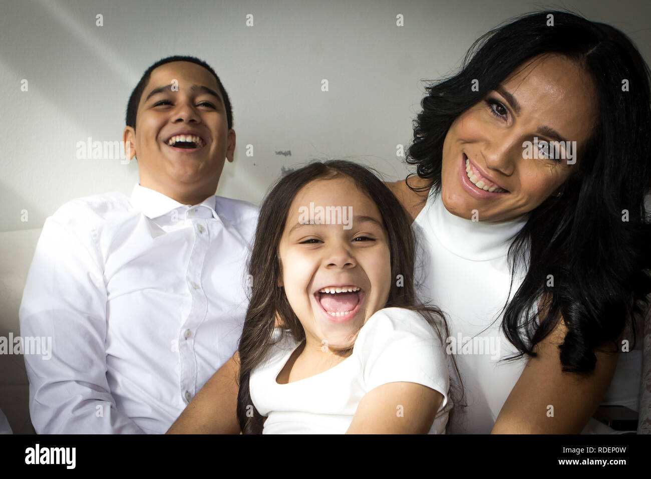 Hispanic Mutter mit Kindern lachen tragen weiße Stockfoto