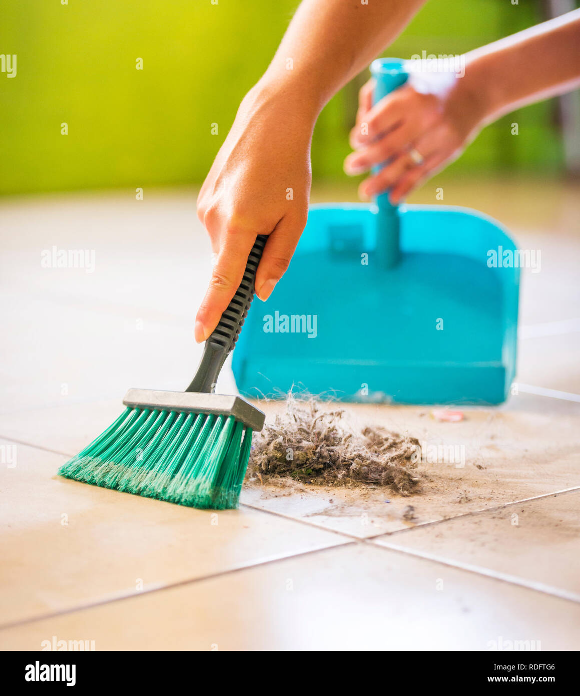 Eine Frau fegt den Staub und Schmutz vom Boden, während das Haus reinigen Stockfoto