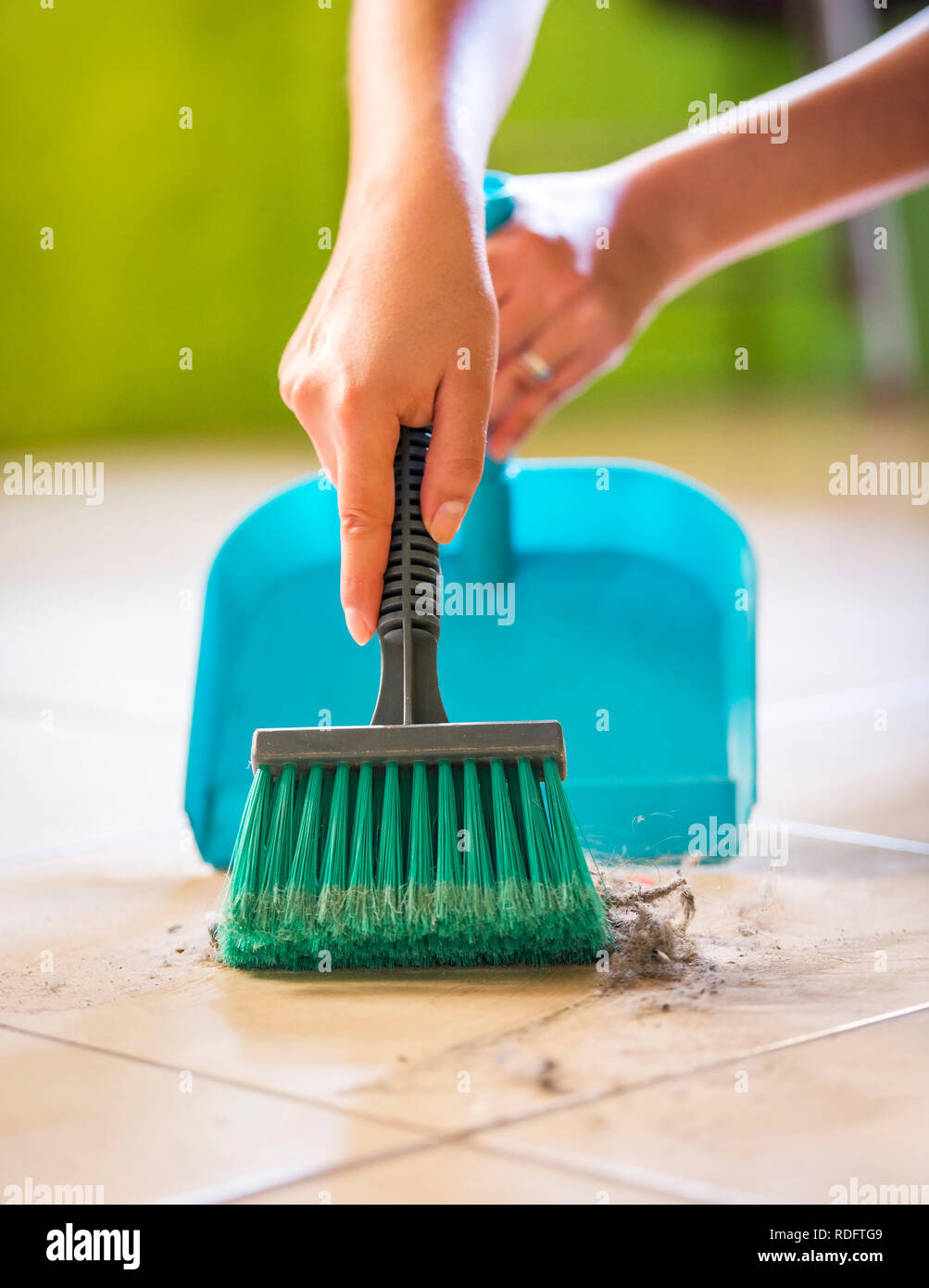 Eine Frau fegt den Staub und Schmutz vom Boden, während das Haus reinigen Stockfoto