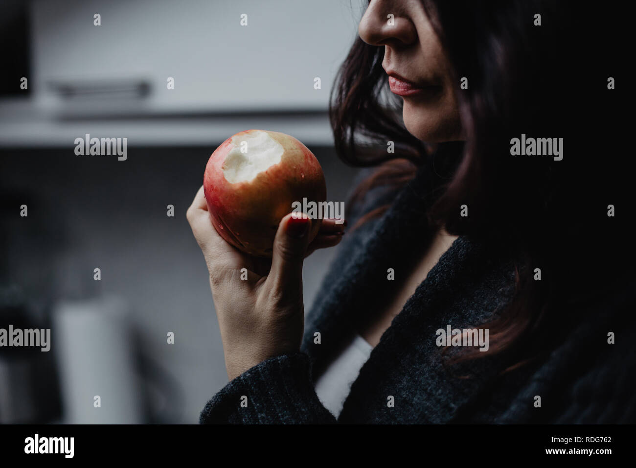 Schöne brünette Frau mit einem Apfel in der Küche Stockfoto