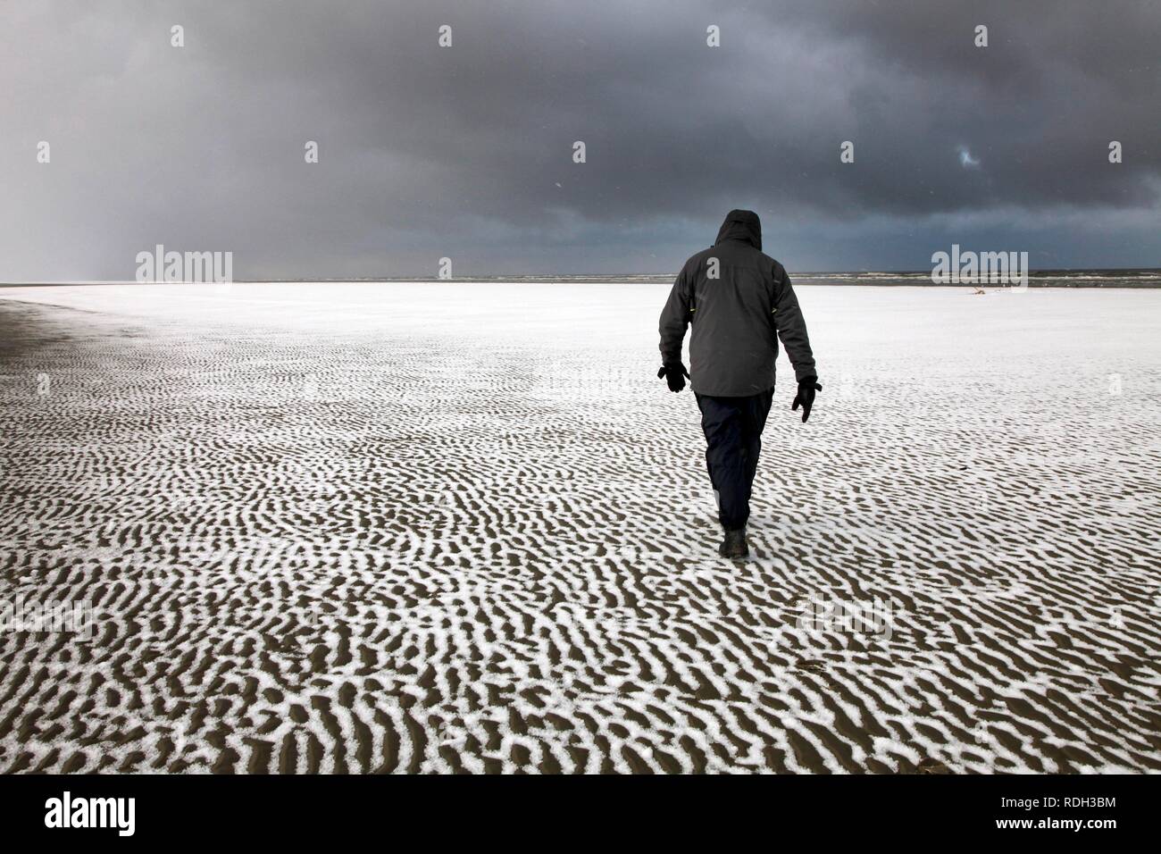 Person zu Fuß entlang der verschneiten Strand auf der ostfriesischen Nordseeinsel Spiekeroog, Niedersachsen Stockfoto