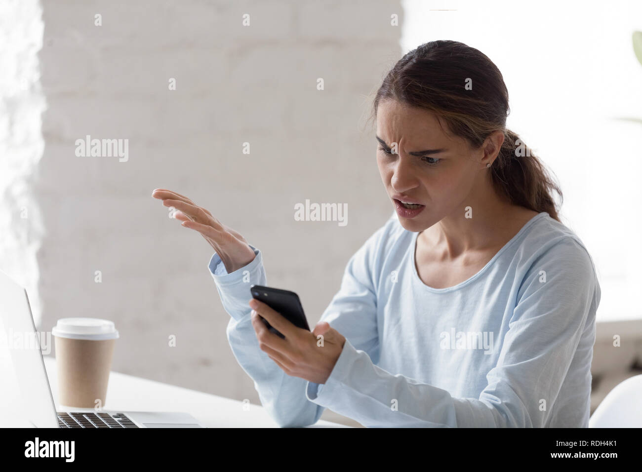 Wütende Frau in Problem mit Telefon verwirrt, schlechte Nachrichten lesen Stockfoto