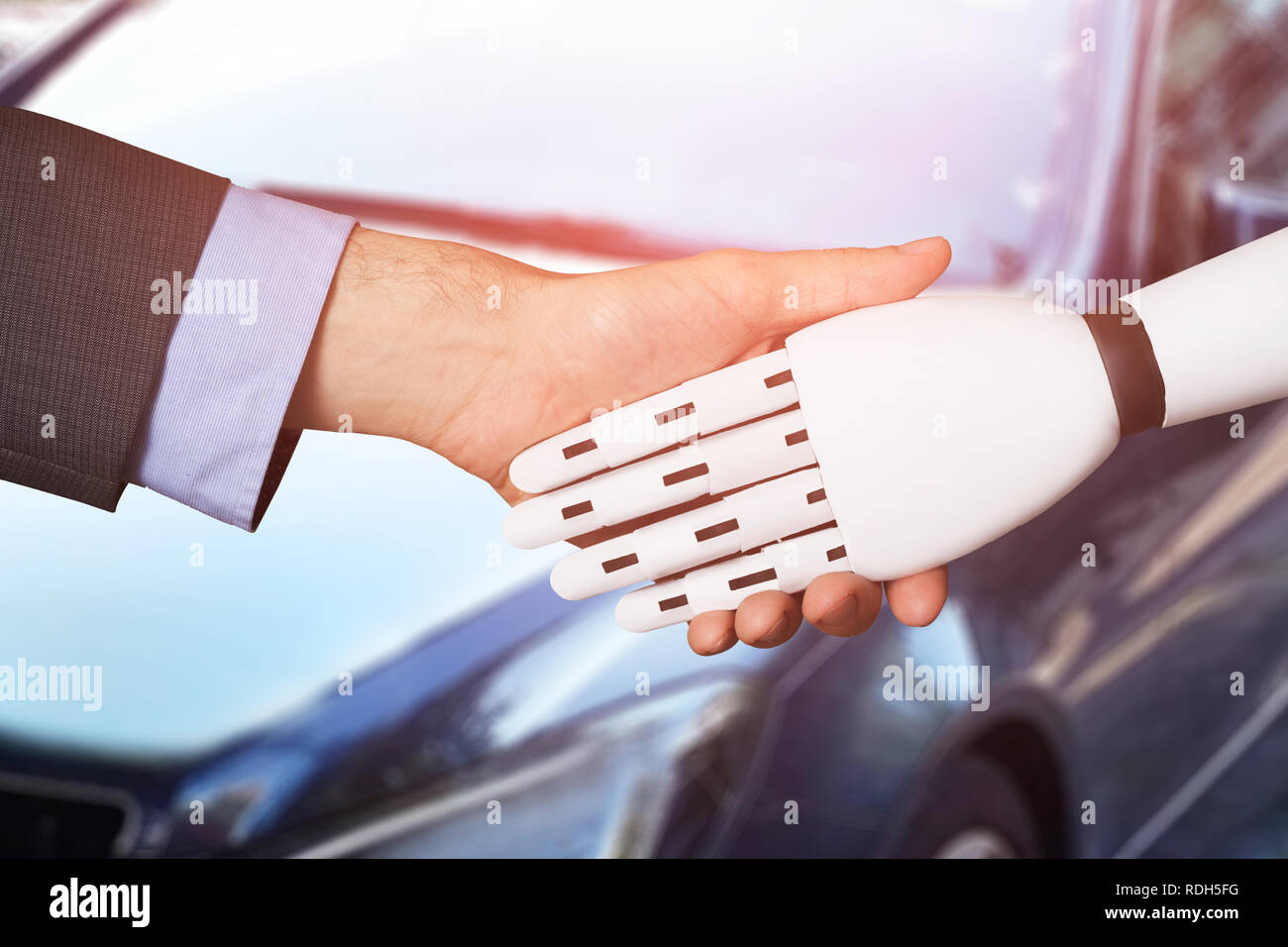 Nahaufnahme eines Menschen die Hände schütteln mit Roboter Vor dem Auto Stockfoto