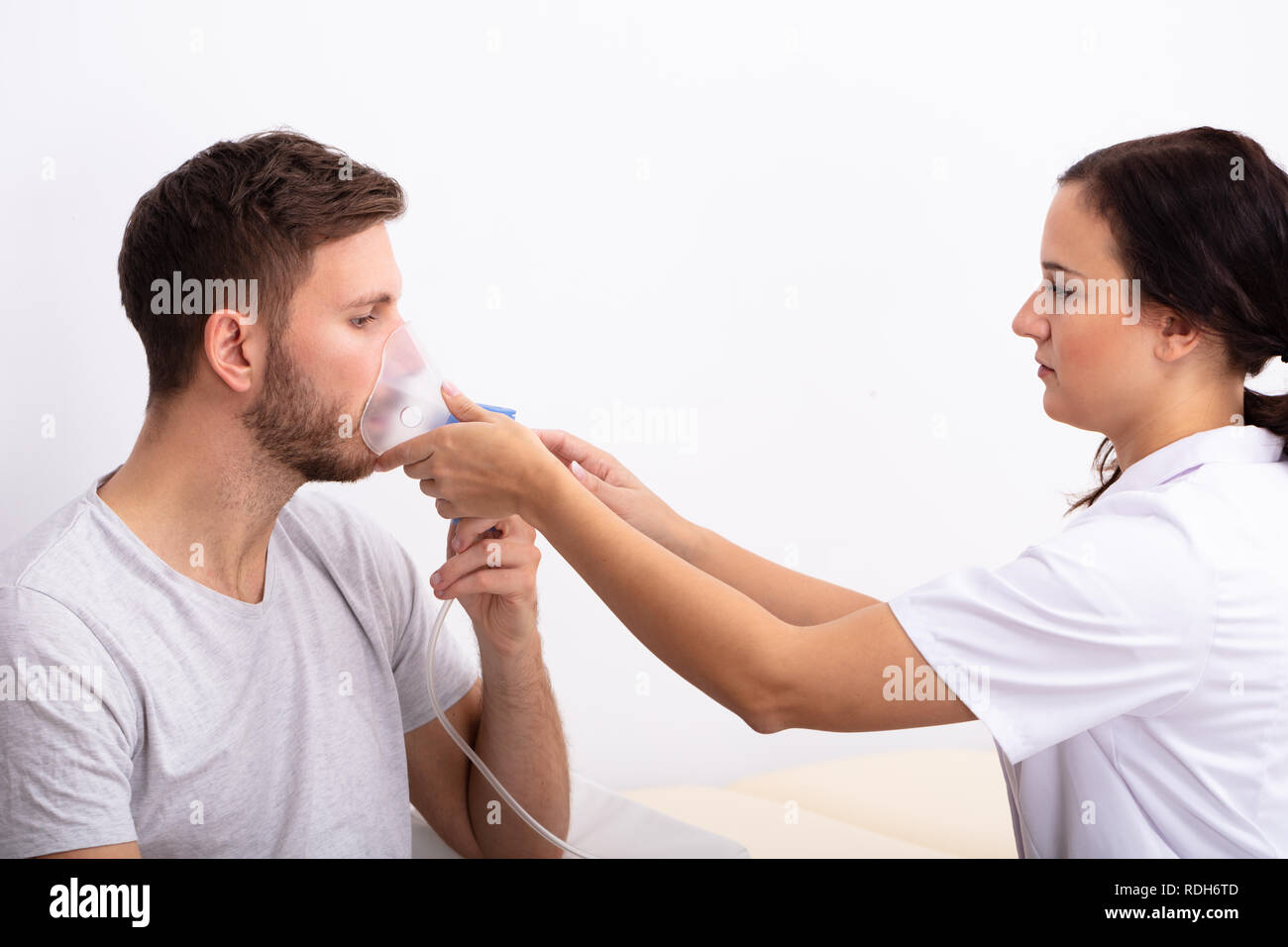 Seitenansicht der jungen Ärztin Holding Sauerstoff Maske über die männlichen Patienten Mund Stockfoto