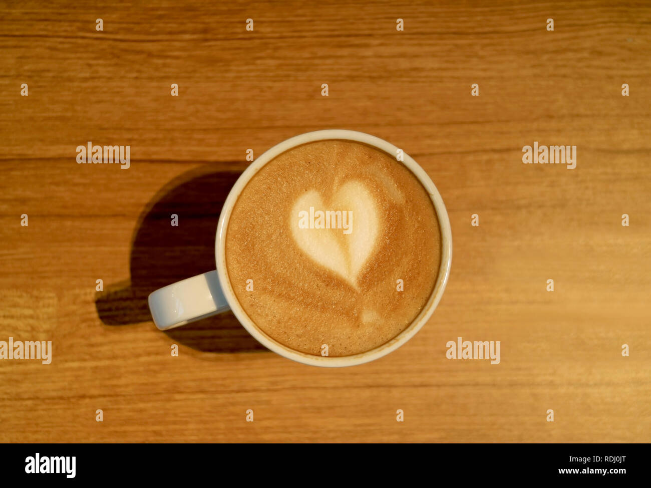 Herzförmige Latte Art der heißen Cappuccino mit Latte Art in einem weißen Schale serviert auf hölzernen Tisch Stockfoto