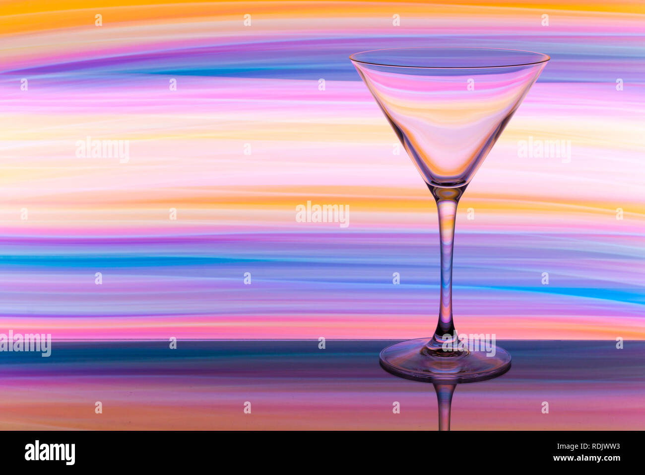 Einen einzigen cocktail/Martini Glas mit einem Regenbogen aus vielfarbigem Licht Malerei hinter Stockfoto