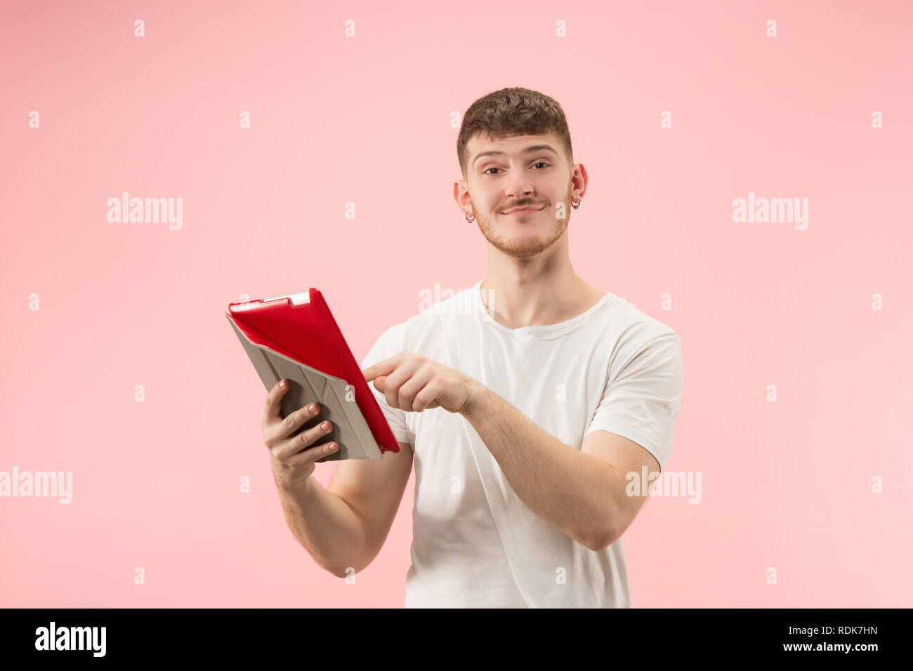 Portrait von lächelnden Mann am Laptop mit leeren Bildschirm auf Pink Studio Hintergrund zeigt. Menschliche Gefühle, Mimik Konzept und Werbung Konzept. Stockfoto