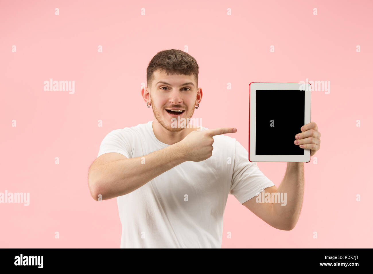 Portrait von lächelnden Mann am Laptop mit leeren Bildschirm auf Pink Studio Hintergrund zeigt. Menschliche Gefühle, Mimik Konzept und Werbung Konzept. Stockfoto