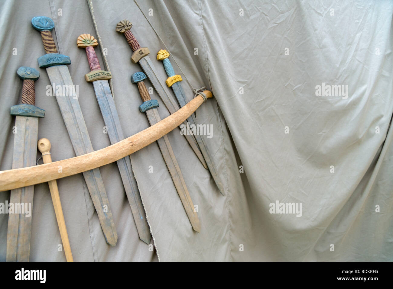 Holz- handgemachte Schwerter hängt am Seil auf grauer Stoff Hintergrund. Mittelalterliche Waffen für Nahkampf auf grauem Stoff Textur angezeigt Stockfoto