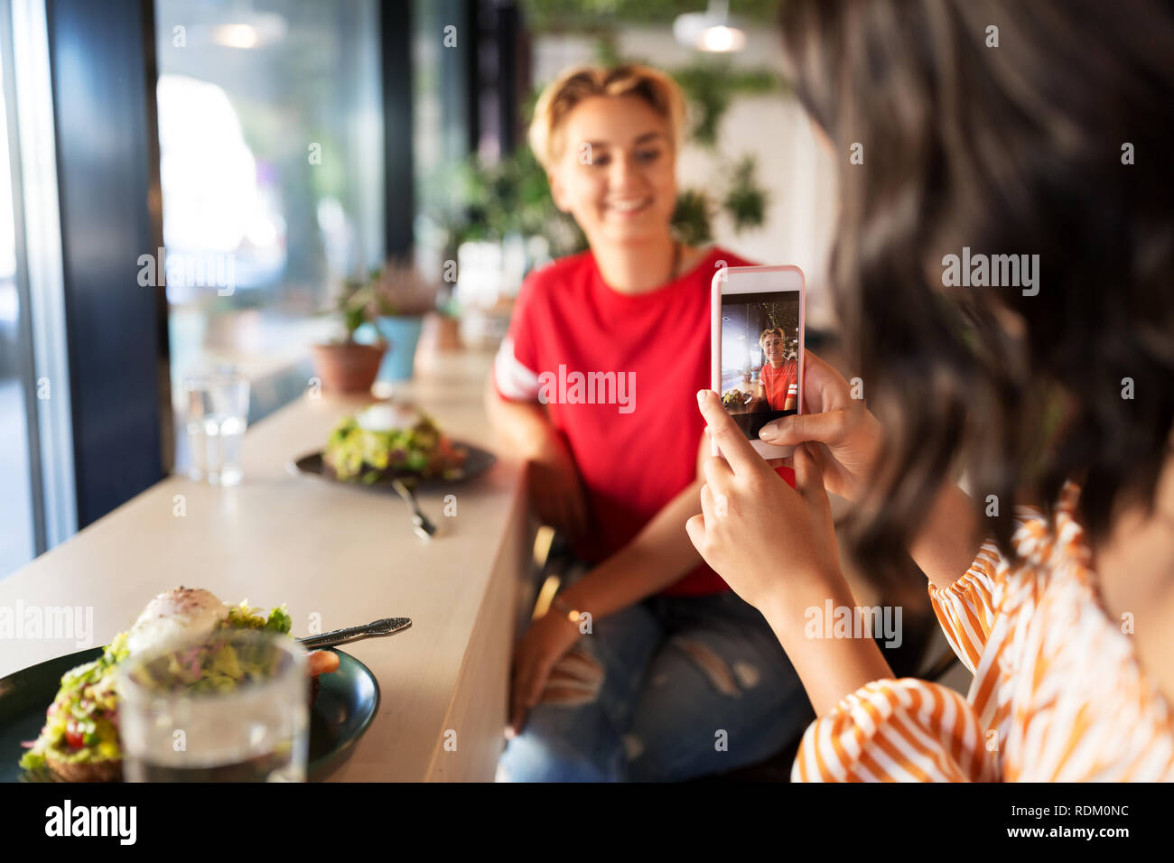 Frauen mit Mittagessen und Fotografieren im Cafe Stockfoto