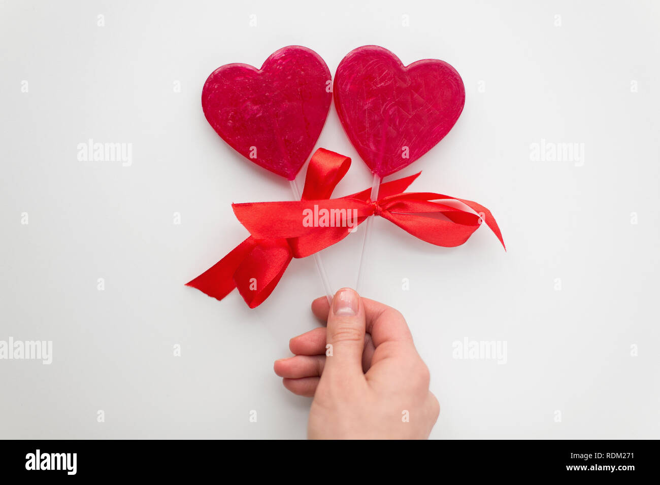 Nahaufnahme einer Hand, die rote herzförmige Lollipop Stockfoto