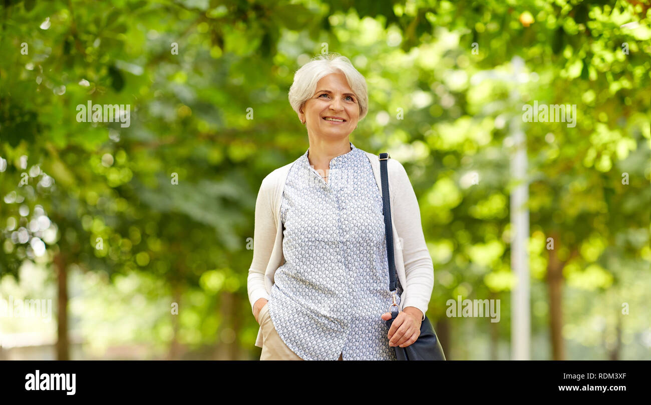 Gerne ältere Frau mit Handtasche am Sommer, Park Stockfoto