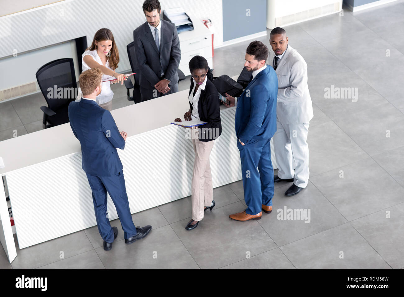 Junge Frau an der Rezeption erklärt Geschäftsmann Stockfoto