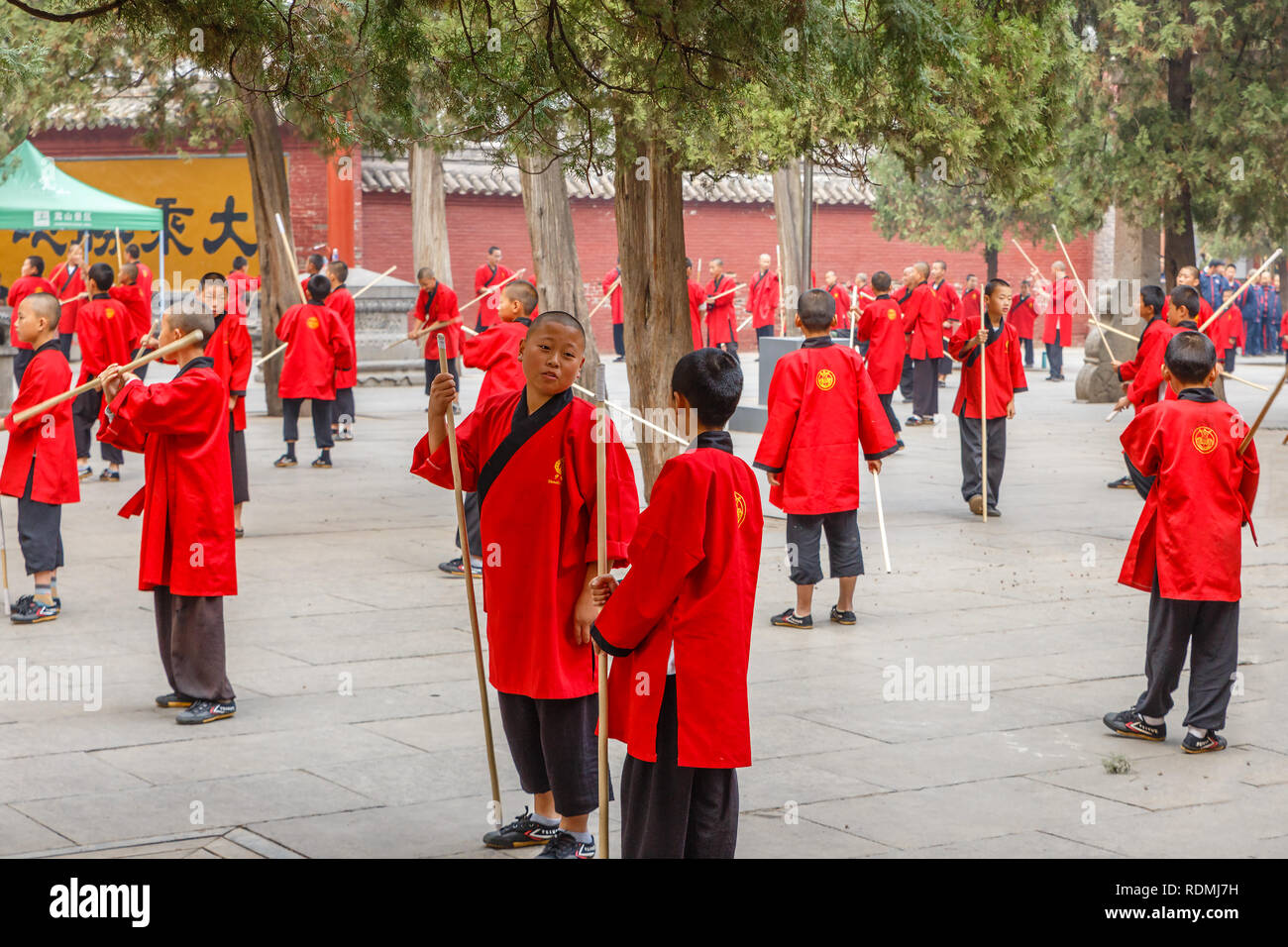 Dengfeng, China - Oktober 16, 2018: Schüler der Martial Arts School sind mit Stöcken auf dem Platz vor dem Tempel beschäftigt.. Shaolin Tempel. Stockfoto