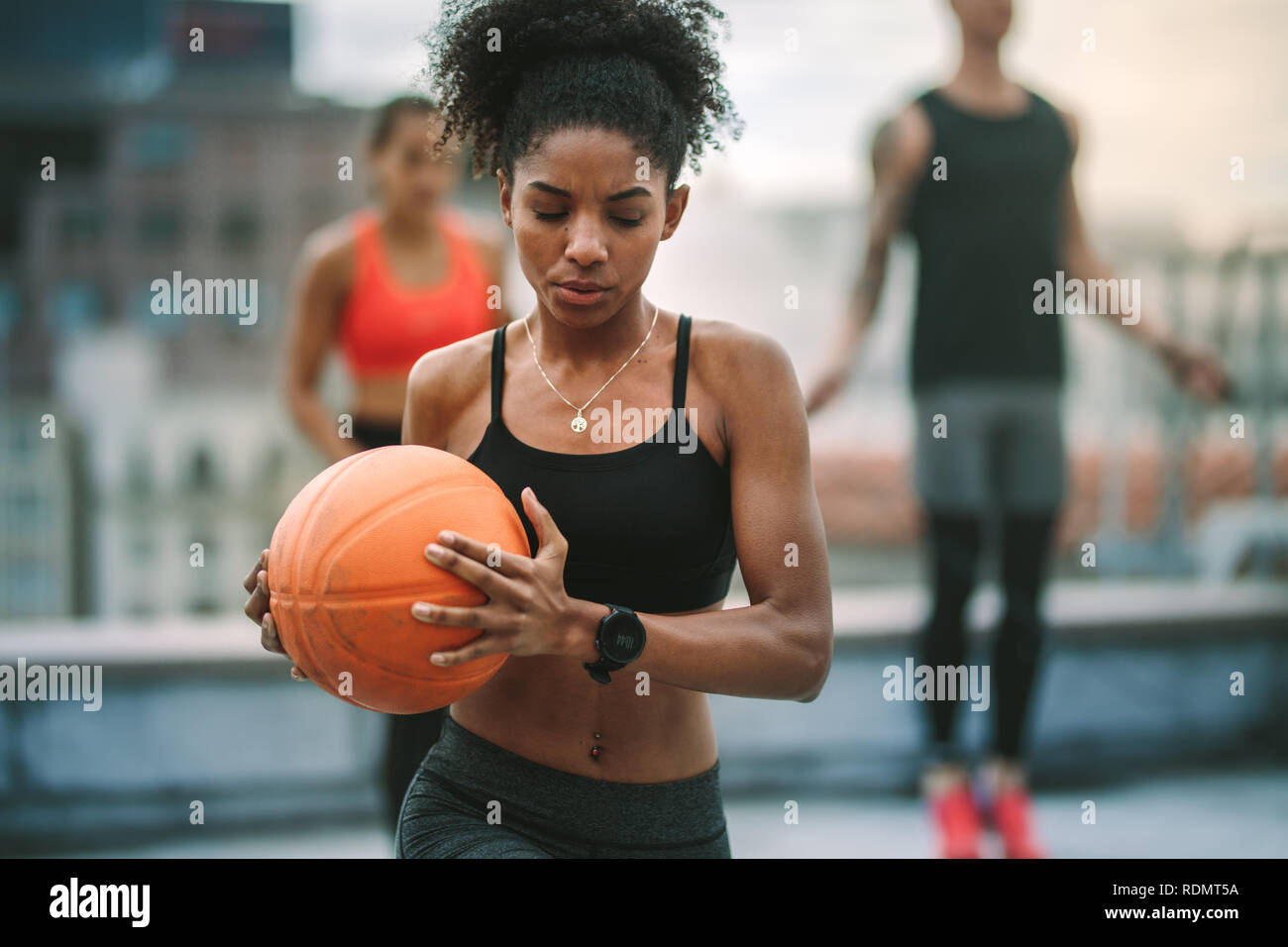 Nahaufnahme eines afro-amerikanische fitness Frau tun Fitness Training mit einem Basketball. Weibliche Athlet, Training auf der Dachterrasse mit einem Mann und Frau t Stockfoto