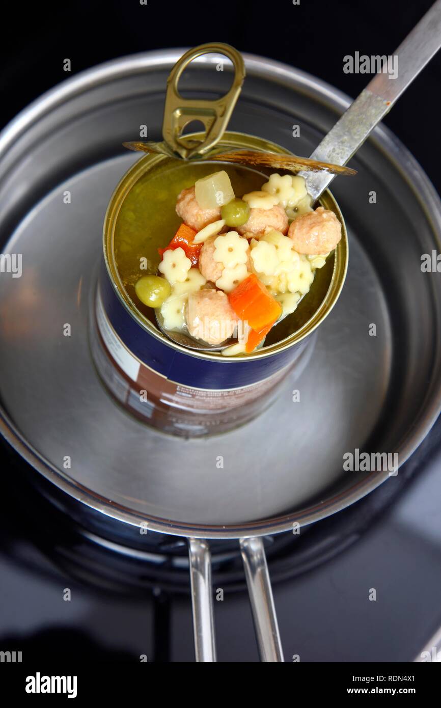 Nacherwärmung ein fertiggericht in eine Blechdose im Wasserbad, Nudelsuppe mit Frikadellen und Gemüse Stockfoto