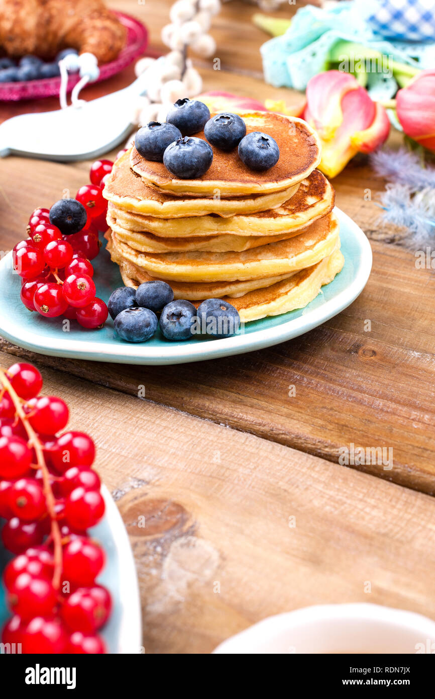 Sie hausgemachte Kuchen Croissants zum Frühstück mit Heidelbeeren und Johannisbeeren und Kaffee, auf einer hölzernen Hintergrund und Frühling Tulpen. Freier Platz für Text Stockfoto