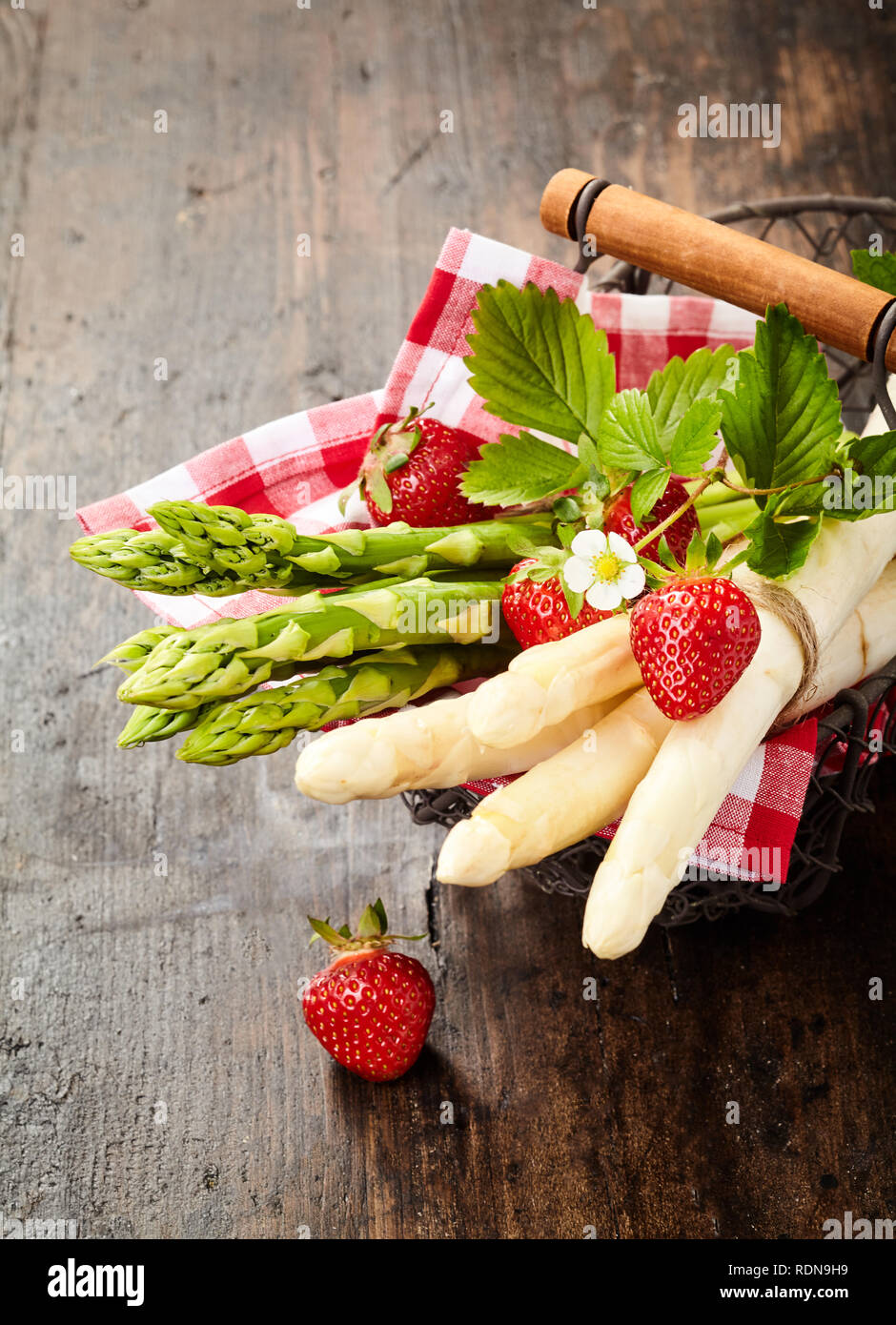 Frische Trauben von Gourmet Grüner und Weißer Spargel Tipps für ein Tuch in einem rustikalen Drahtkorb mit frischen Erdbeeren Stockfoto