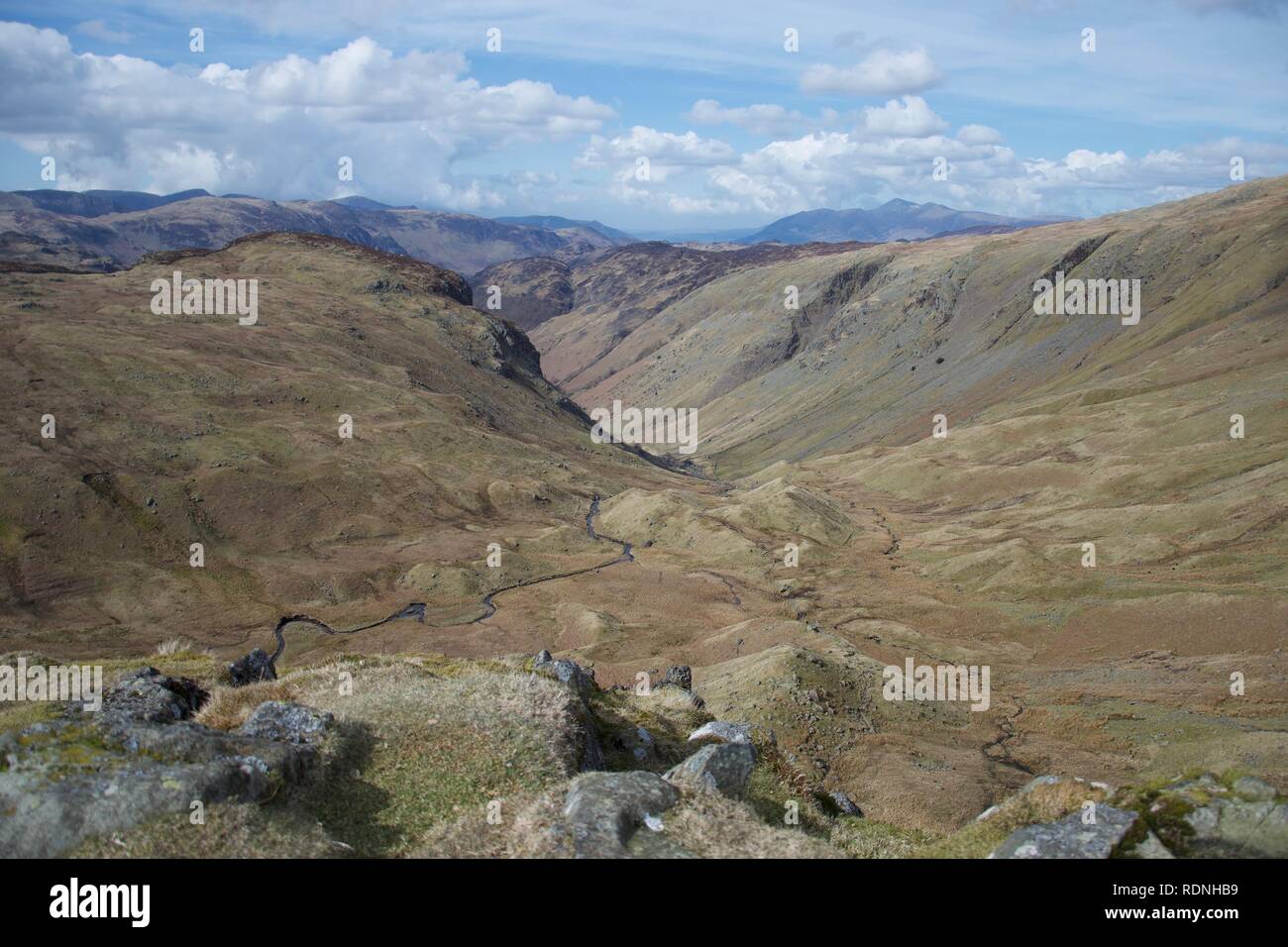 Ausblick In einem sumpfigen Tal, von einem fiel im englischen Lake District (Cumbria, UK). Felsen im Vordergrund und einem mäandernden Stream/riv Stockfoto