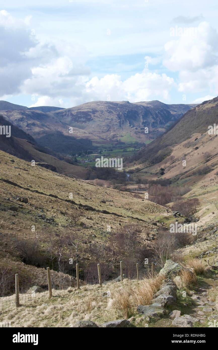 Braun, grasartigen, sumpfigen Tal im Norden von England (Lake District, Cumbria), mit Stream und taumeln Felsen oder Steinen. Grünen Felder des farml Stockfoto