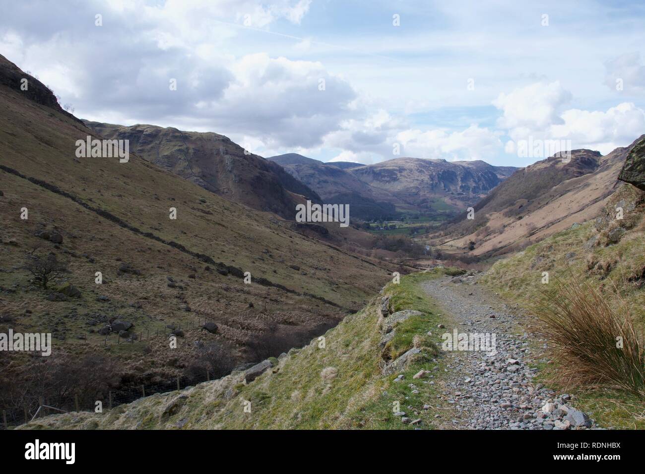 Grauen Stein Fußweg und Gras im Vordergrund Moor. Ein Tal im Norden von England (Lake District, Cumbria), mit Ackerland in der Ferne, Smal Stockfoto