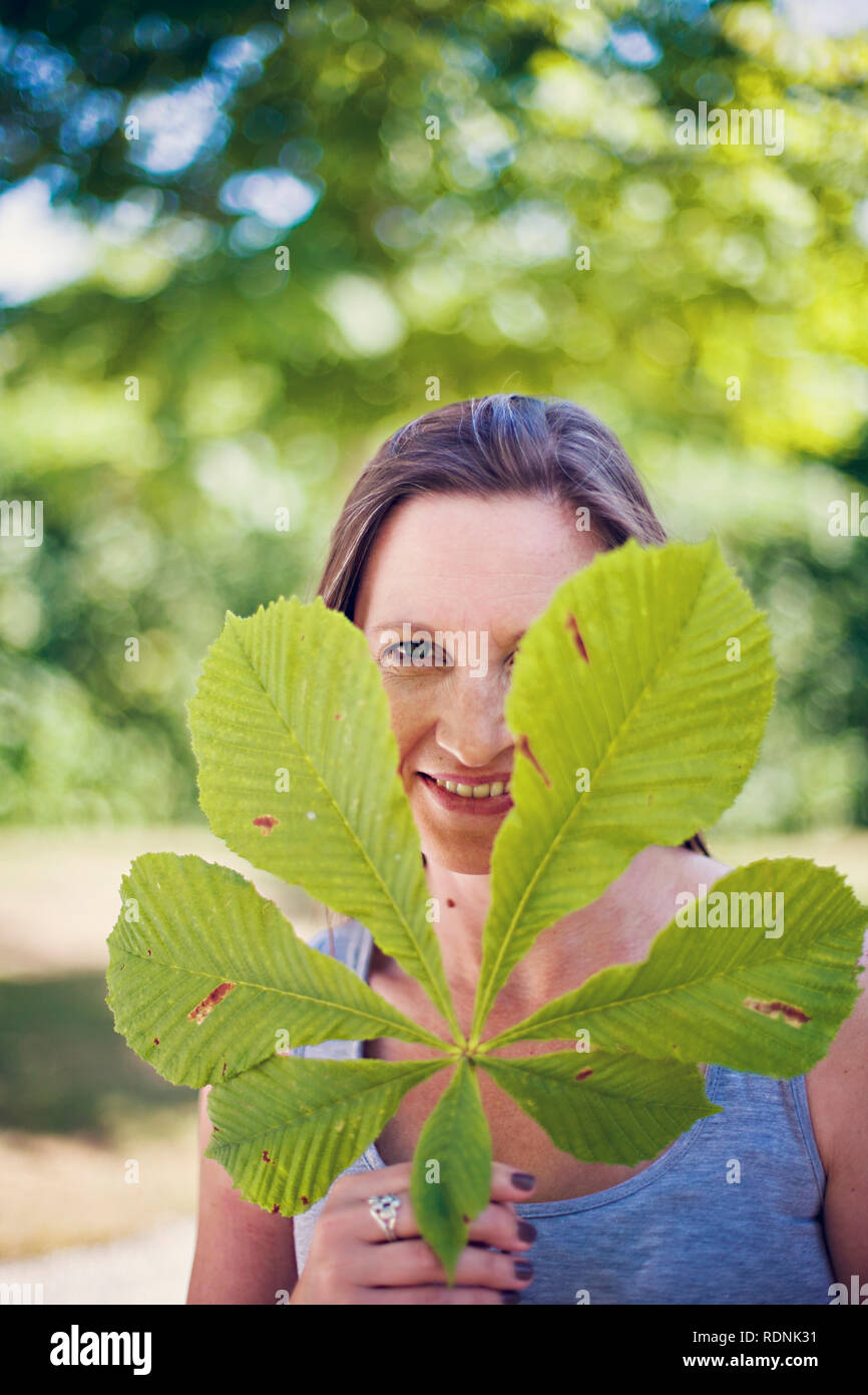 Porträt der lächelnde Frau mit Kastanien Blatt Stockfoto