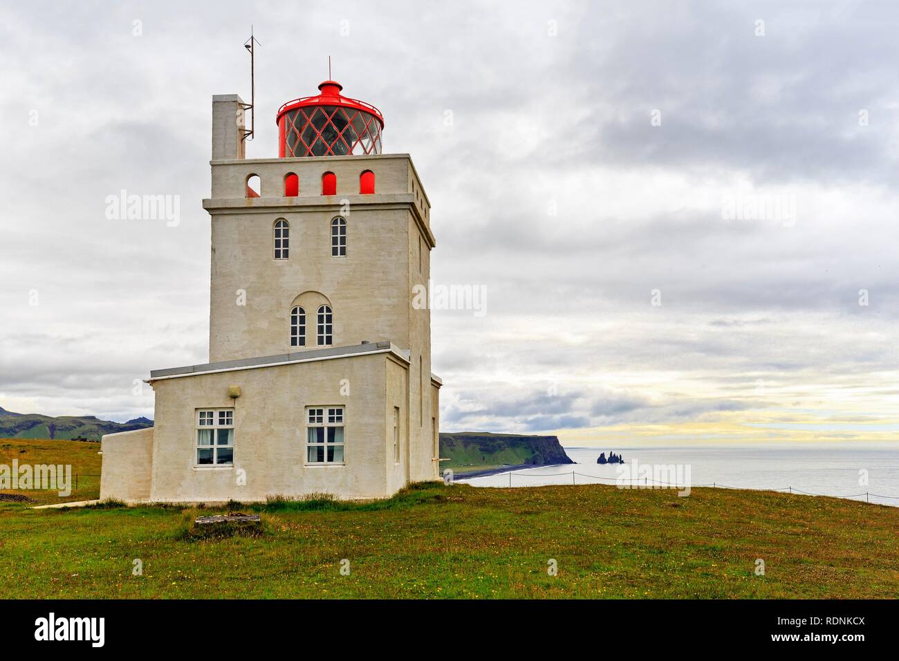 Leuchtturm am Kap Dyrhólaey, Dyrholaey, nächsten Reynisdrangar, felsnadeln vor der Küste von Vík Vík í Mýrdal, Stockfoto