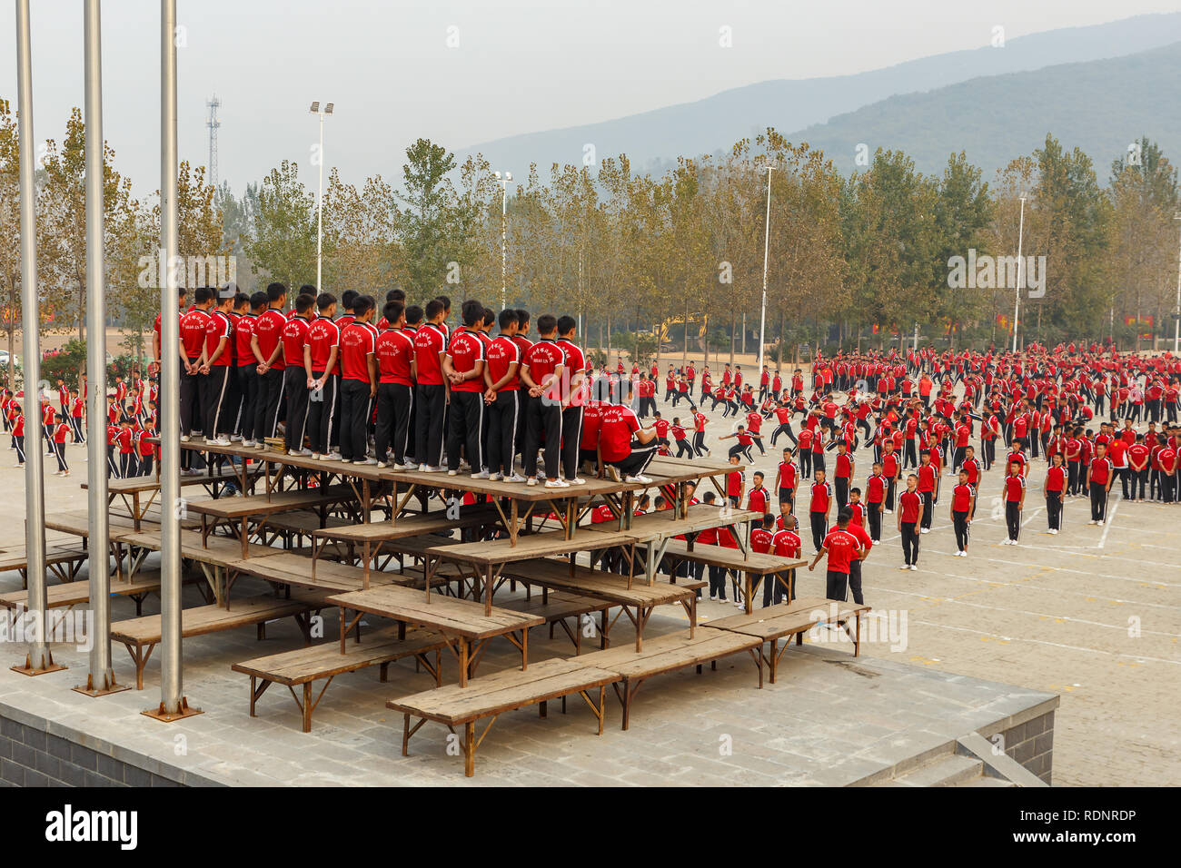 Dengfeng, China - Oktober 16, 2018: Schüler der Martial Arts School zusammen mit der Lehrerin beobachte, wie andere Schüler trainieren. Shaolin Tempel. Stockfoto