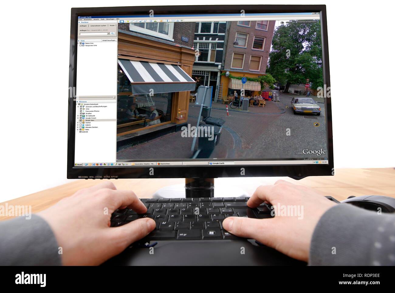 Person sitzen an einem Computer arbeiten mit Google Street View, Bildschirm und zeigt ein detailliertes Bild der Teil der Innenstadt von Stockfoto