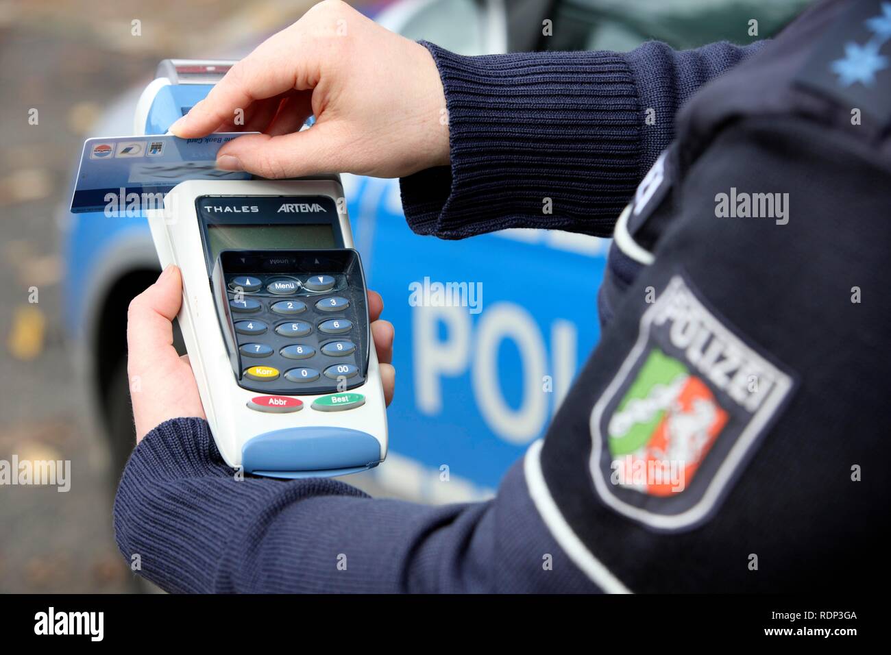 Polizeioffizier mit BARVUS Gerät für die bargeldlose Zahlung von Kaution, Geldbußen, Tickets mit Kreditkarte Stockfoto