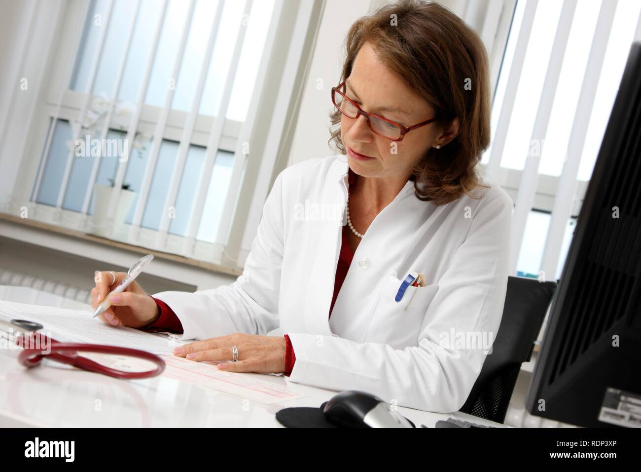 Die medizinische Praxis, Arzt Untersuchung der Gesundheitsdaten eines Patienten an ihrem Schreibtisch Stockfoto