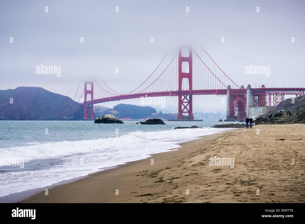 Menschen zu Fuß auf einem Sandstrand in der Nähe der Golden Gate Bridge, San Francisco, Kalifornien Stockfoto
