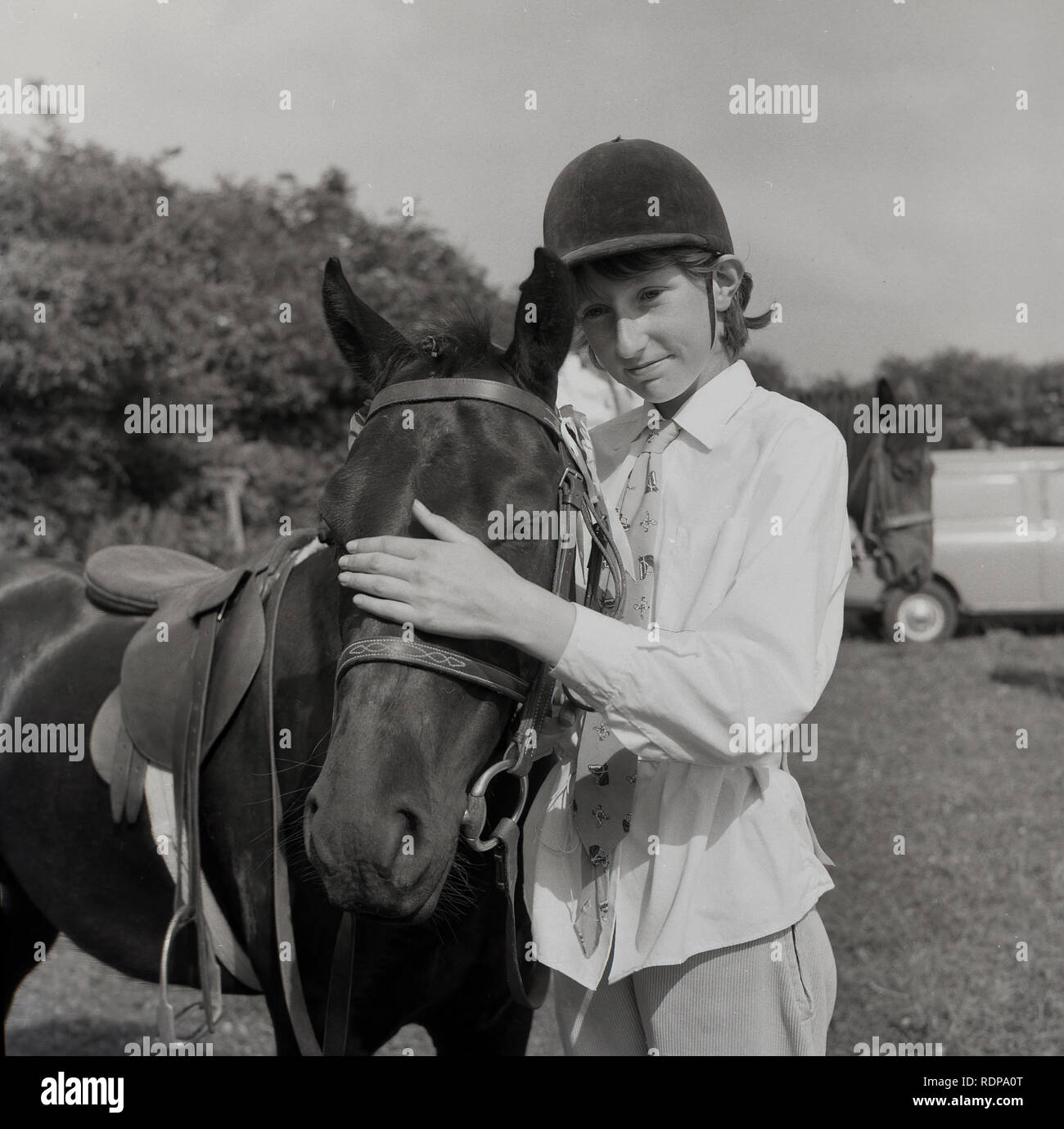 1967, historisch, draußen auf einem Feld bei einer Reitveranstaltung, Mädchen Reiterin streichelte die Stirn ihres Pferdes, England, Großbritannien. Stockfoto