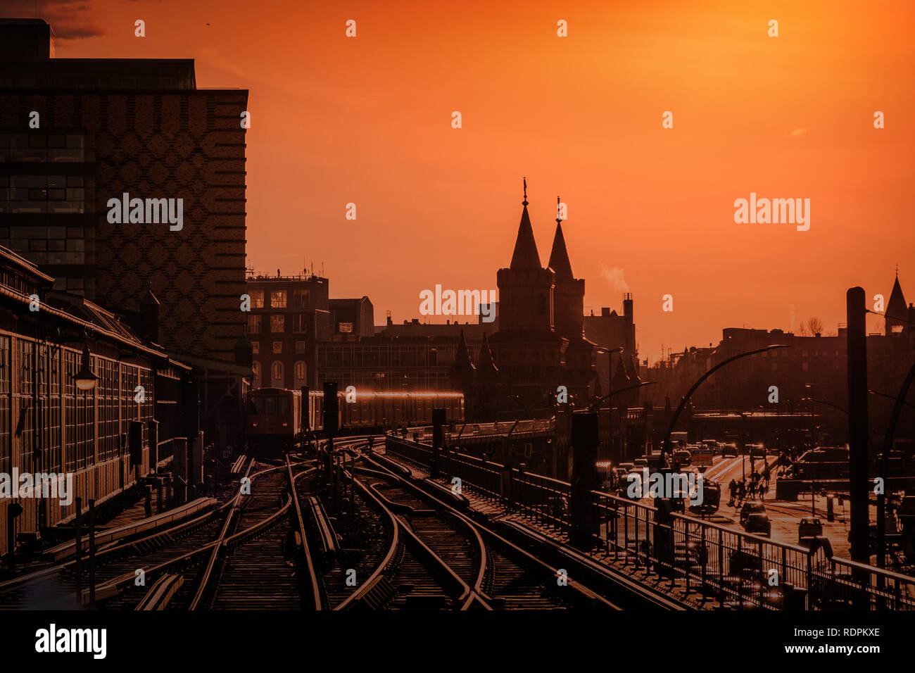 Berliner Stadtbild bei Sonnenuntergang mit dem Zug über Oberbaumbrücke zwischen Kreuzberg und Friedrichshain. Stockfoto