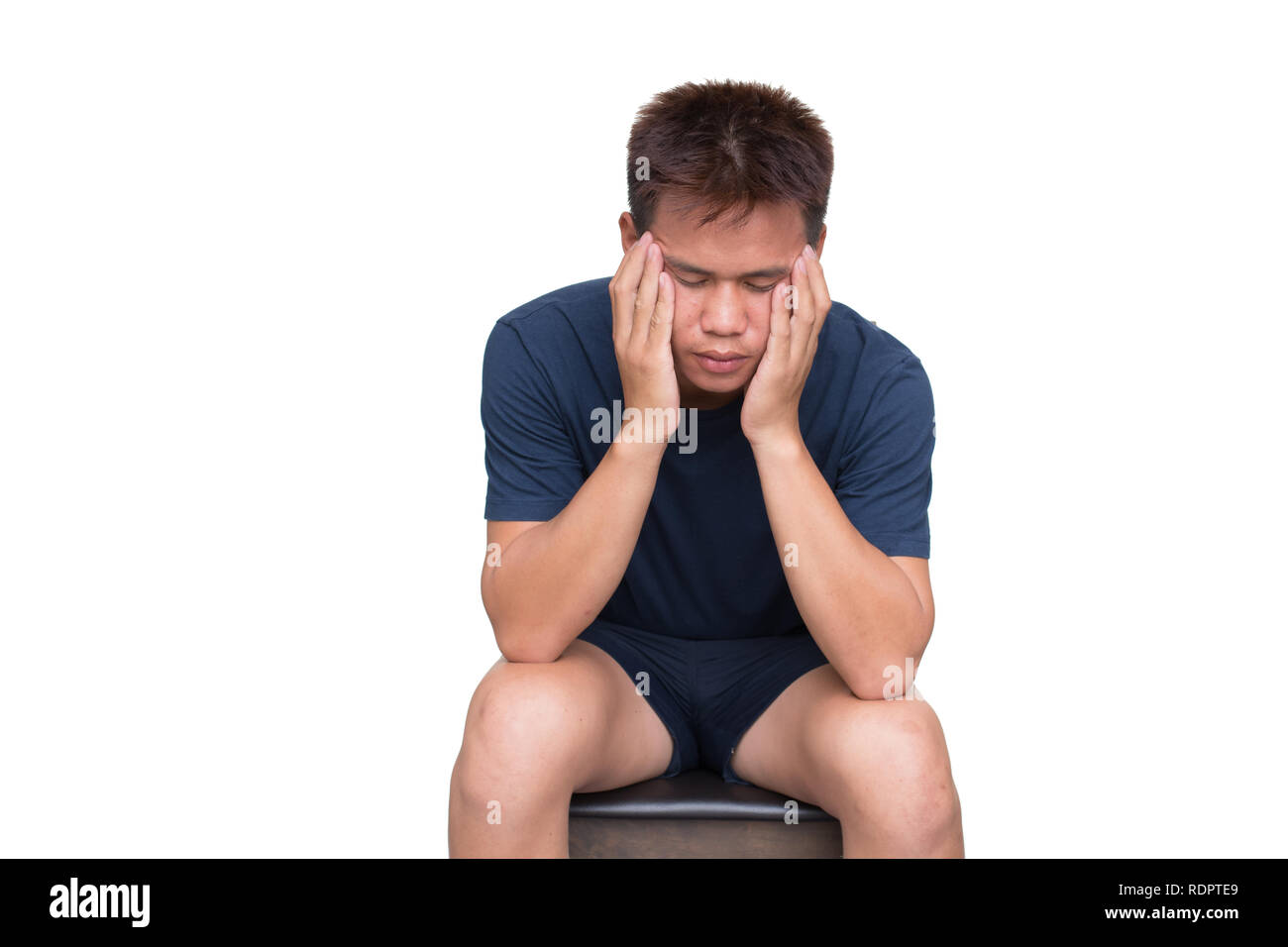 Junger Mann auf der Suche ängstlich und besorgt, mit Kopfschmerzen auf dem Stuhl auf weißem Hintergrund. Mit Freistellungspfad Stockfoto