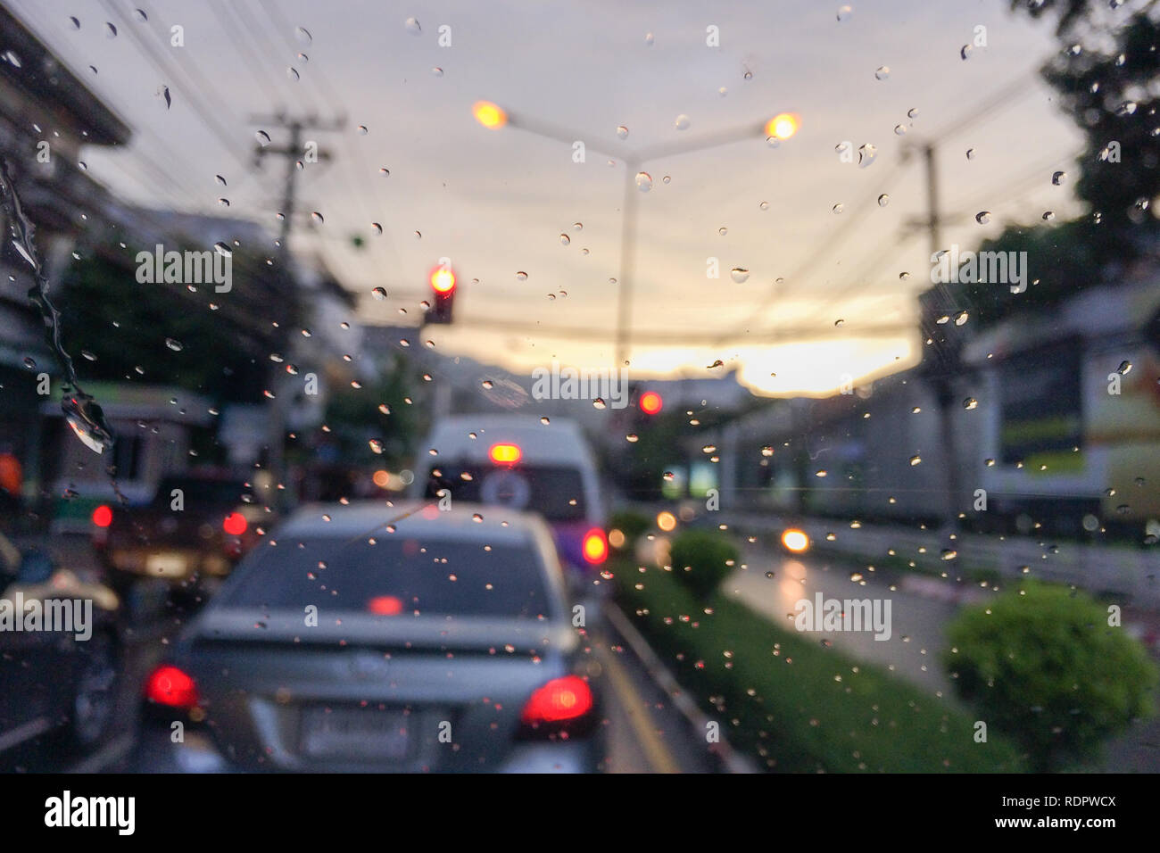 Regen fällt auf Auto Fenster vorne mit blur Stau in Abend. Stockfoto